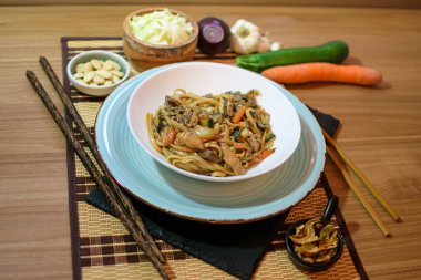 Sebzeli pirinç eriştesi ve beyaz kasede et. Ahşap arka. Kapatın. Üst görünüm