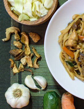 Sebzeli pirinç eriştesi ve beyaz kasede et. Koyu yeşil arka plan. Kapatın. Üst görünüm