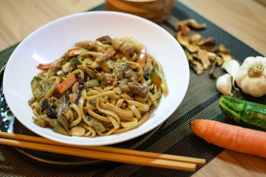 Sebzeli pirinç eriştesi ve beyaz kasede et. Koyu yeşil arka plan. Kapatın. Üst görünüm