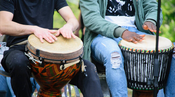 Drummer hands playing the ethnic djembe drum outside.