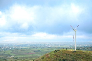 Sicilya 'daki tepede açık mavi gökyüzü arka planına sahip yel değirmenleri türbinleri. Kırsal kesimde yenilenebilir enerji ve çevre bakımı kavramı