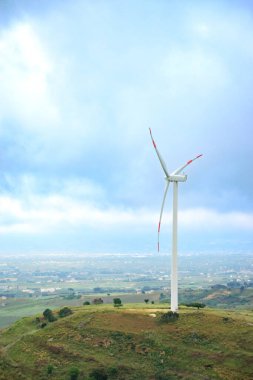 Sicilya 'daki tepede açık mavi gökyüzü arka planına sahip yel değirmenleri türbinleri. Kırsal kesimde yenilenebilir enerji ve çevre bakımı kavramı