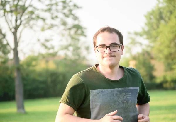 Fiatal Férfi Szemüveggel Zöld Pólóval Parkol Fűvel Napsütéses Nappal — Stock Fotó