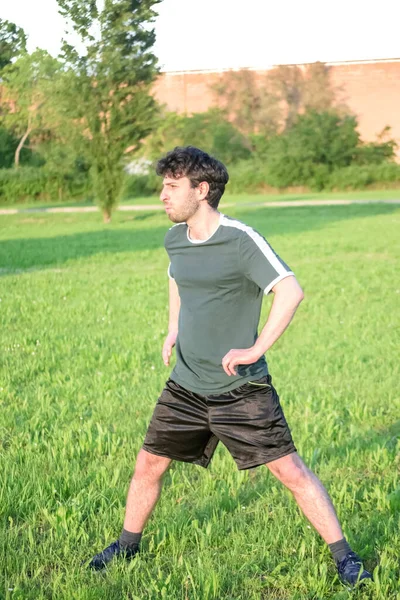 Mladý Muž Zeleným Tričkem Cvičení Strečink Parku Trávou Slunečným Dnem — Stock fotografie