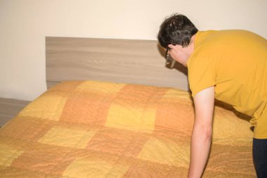 Yeni nesil inek gözlüklü, sarı tişörtlü, elektrikli süpürge kullanan genç bir adam.