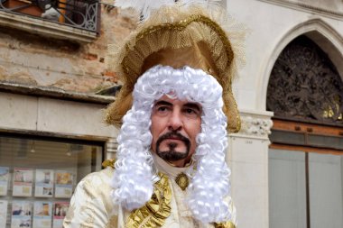 Person dressed up for Carnival of Venice wearing golden clothes.