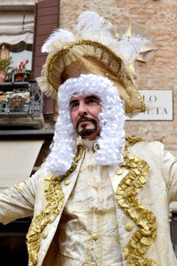 Person dressed up for Carnival of Venice wearing golden clothes.