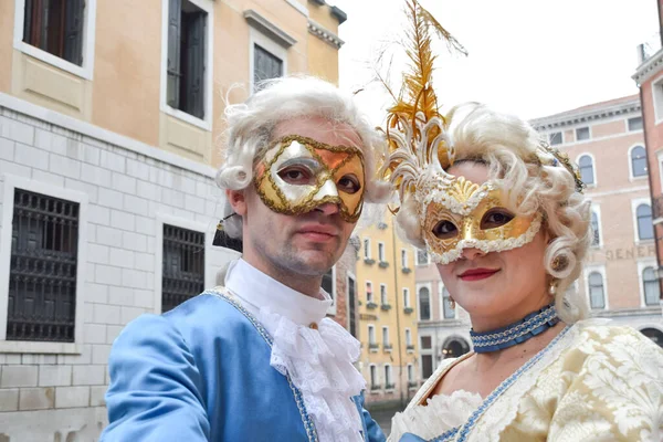 Couple dressed up for the Venice Carnival wearing contemporary clothes.