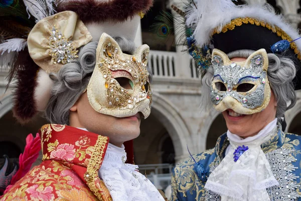 Couple of people dressed up for the Venice Carnival wearing cat masks.