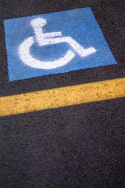 Asfalt üzerinde sarı çizgileri olan engelliler için park işaretinin eğik resmi