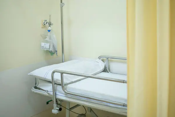 Image of Hospital bed or stretcher with light yellow curtain and purified oxygen behind