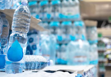 Satılık ve tüketim için süpermarket raflarında depolanmış su şişelerinin resmi