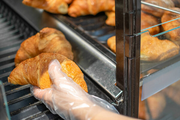 Image of Hand taking Croissants stored for sale and consumption. Popular French pastries