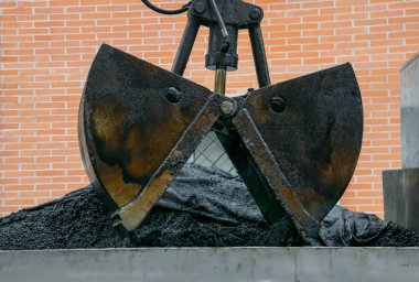 Kazıcının asfalt boşaltma işlemindeki resmini kapat