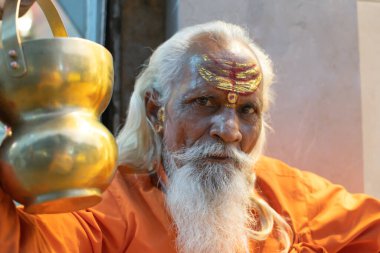 Hindistandaki sofu keşiş Sadhu, sakallı, beyaz saçlı ve yüzü boyalı kameraya bakarak vaaz veriyor.