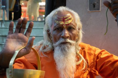 Hindistandaki sofu keşiş Sadhu, sakallı, beyaz saçlı ve yüzü boyalı kameraya bakarak vaaz veriyor.