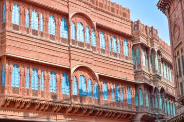 View of Dulmera Havelis in Bikaner with windows in green tones and touristy red facades, India. clipart