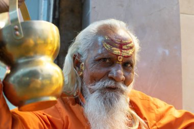 Hindistandaki sofu keşiş Sadhu, sakallı, beyaz saçlı ve yüzü boyalı kameraya bakarak vaaz veriyor.