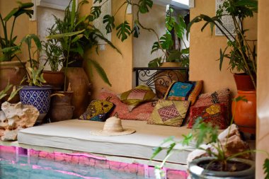 Renkli yastıklı bale yatağı, dekoratif bitkiler, Marakeş 'te bir şapka ve yüzme havuzu. Fas
