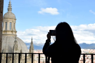 Arka planda, yüksek bir kilisenin fotoğrafını çeken genç bir kadın var. Segovia, İspanya.