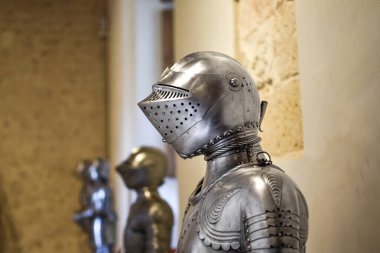 Ortaçağ parlak miğferinin detaylarla ve kale duvarındaki diğer zırhlarla yan görüntüsünü kapatın. Segovia, İspanya.