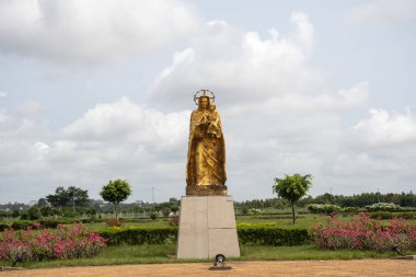 Bakire Meryem 'in altın boyalı heykeli. Bebek İsa' nın kollarında Yamoussoukro 'daki Barış Bakiresi Bazilikası' nın bahçesinde.