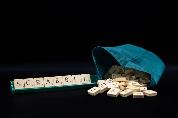 Scrabble Board Game. Word Scrabble from letter tiles in tile rack on the black backgroundwith drawstring letter bag. Studio shot.