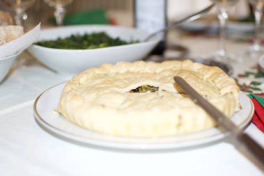 Tipik bir öğle yemeği masası. Bardaklar, bir şişe şarap, ekmek, sebze ve geleneksel İtalyan baharatlı turta.