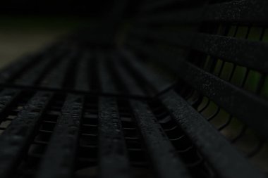 Yağmurdan ıslanmış gri demir bir bank.