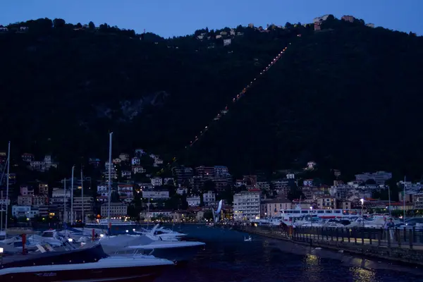 Como, İtalya - 20 Haziran 2023: turistler arka planda gölle birlikte antik Como şehrinin sokaklarında gece vakti geziniyorlar.