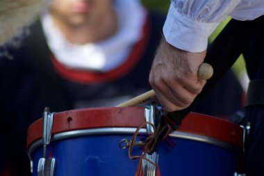 Elinizi ahşap bir değnekle kapatın ve mavi-kırmızı renkli taşınabilir davul çalın.