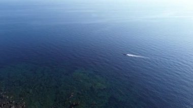 Yazın gün batımında engin mavi denizde sürüklenen bir motorlu aracın sinematografik görüntüsü.