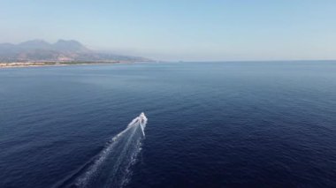 Yazın gün batımında engin mavi denizde sürüklenen bir motorlu aracın sinematografik görüntüsü.
