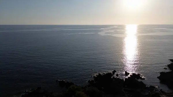 Romantik hava manzarası. Denizde bir gün batımı. Kayaların üzerinde siyah gölgeler.