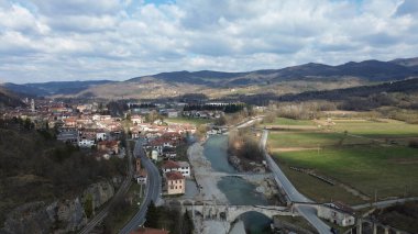 Mavi suyun nefes kesen manzarası Tanaro nehri taşranın yeşil tepelerinden akıyor ve Cuneo eyaletinin Bagnasco kenti yakınlarındaki Roma köprüsü.