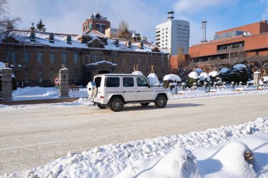 Hokkaido, Japan  - December 20, 2022 : A white luxury Mercedes Benz G-Class driving in downtown Sapporo Hokkaido clipart