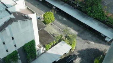 Otoparkı ve küçük bir yeşillik alanı olan modern bir binanın havadan görünüşü.