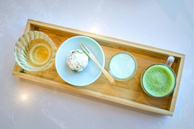 Japon çay seremonisi seti içeren ahşap tepsi, kibrit, wagashi ve bir bardak su.