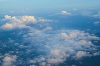 Uçsuz bucaksız mavi gökyüzü tüylü beyaz bulutlarla kaplı. Huzurlu ve huzurlu bir atmosfer yaratıyor.