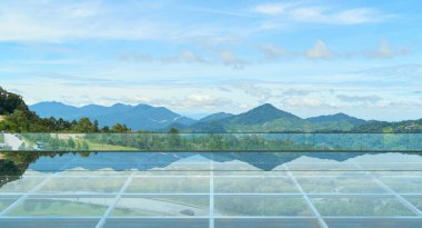 Şeffaf cam zemin platformu görkemli dağları ve dingin mavi gökyüzünü yansıtıyor. Huzur ve korku hissi yaratıyor.