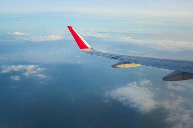 Gün batımında beyaz bulutların üzerinde uçan uçak kanadı