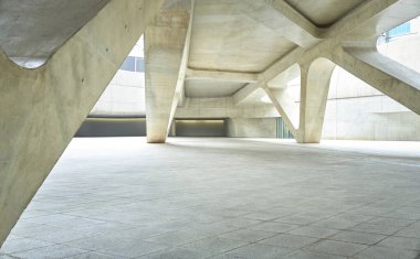 Çağdaş mimari tasarım sergilenen fütüristik beton bir yapının altındaki boş asfaltlı alan