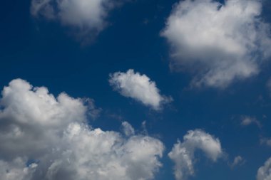 Güzel beyaz kümülüs bulutları derin mavi bir gökyüzünde görülür. Huzurlu ve huzurlu bir atmosfer yaratır.