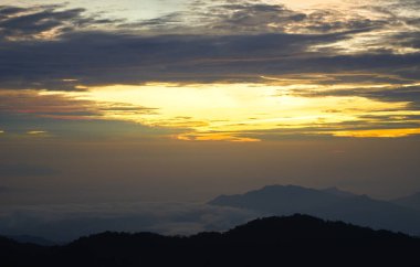 Altın gün doğumu gökyüzünü sisli bir dağ silsilesinin üzerine boyar. Genting Highlands, Malezya 'da nefes kesici bir manzara yaratır.
