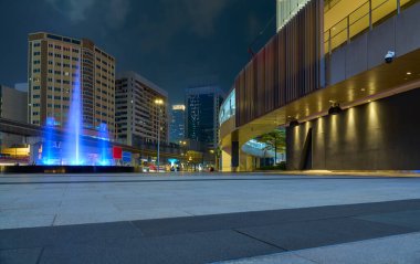 Kuala lumpur urban cityscape at night with a vibrant blue fountain, modern architecture, and street lights