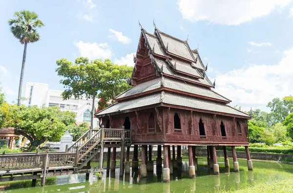 The old wooden church built in Buddhism in the pool, Ubon Ratchathani, Thailand, on background blue sky with white clouds.