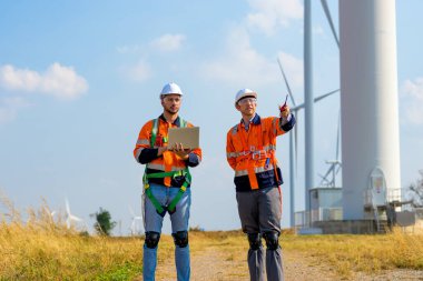 Technician working outdoor at wind turbine field. Environmental engineer research and develop approaches to providing clean energy sources