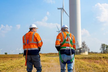 Technician working outdoor at wind turbine field. Environmental engineer research and develop approaches to providing clean energy sources