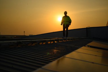 Silhouette of technician engineer checking and repairing solar panels on rooftop of solar cell farm power plant, Renewable energy source for electricity and power