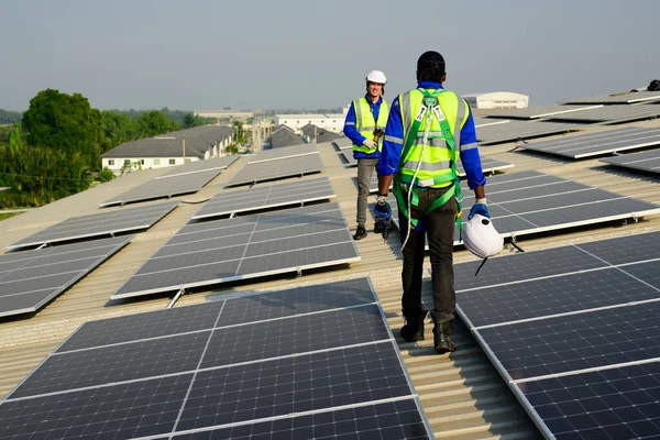 Professional technicians installing solar panels on rooftop of plant, Workers checking and operating system at solar cell farm power plant, Renewable energy source for electricity and power, Solar